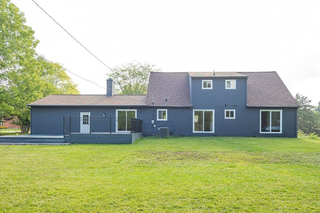 rear view of property featuring central AC, stucco siding, a chimney, a yard, and a deck