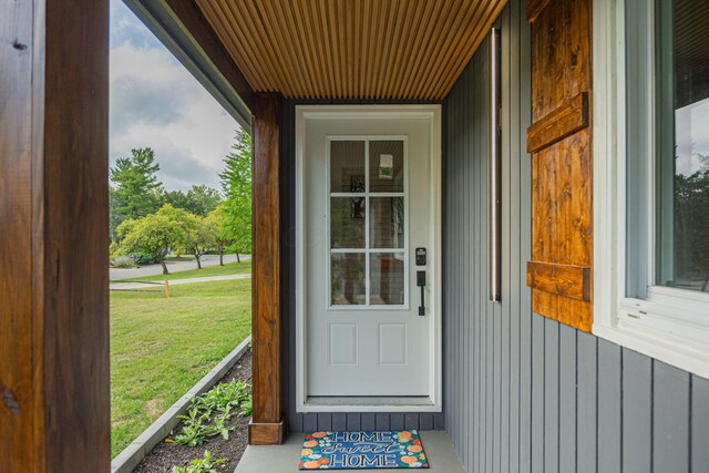 doorway to property with a lawn and board and batten siding