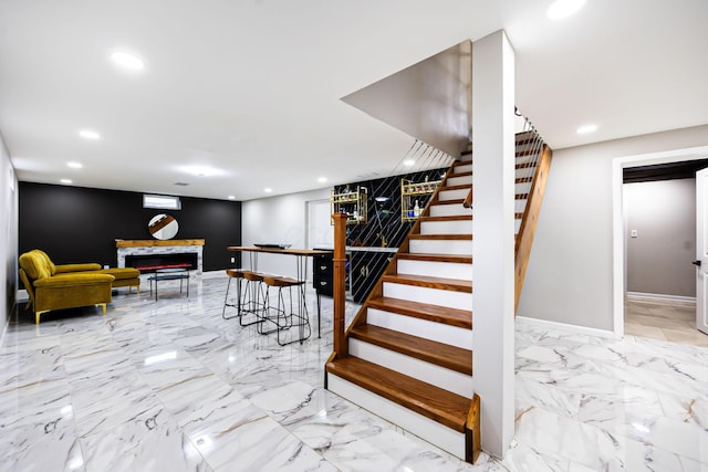 stairway featuring recessed lighting, baseboards, marble finish floor, and a warm lit fireplace