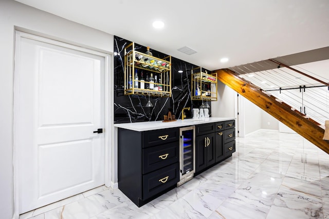 bar featuring indoor wet bar, recessed lighting, marble finish floor, and beverage cooler