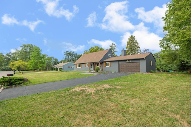 view of front of property featuring a chimney, driveway, a front lawn, and a garage