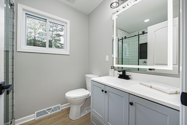 full bathroom featuring wood finished floors, baseboards, visible vents, tiled shower, and toilet