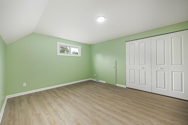 unfurnished bedroom with visible vents, lofted ceiling, baseboards, and light wood finished floors