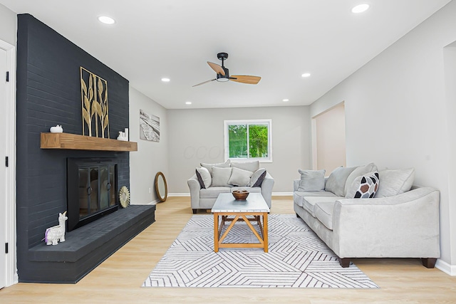 living area featuring recessed lighting, a brick fireplace, baseboards, and wood finished floors