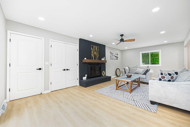 living area with recessed lighting, baseboards, light wood-style flooring, and a fireplace