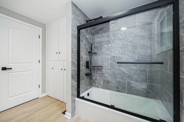 bathroom featuring wood finished floors and enclosed tub / shower combo