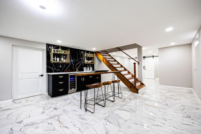 bar featuring beverage cooler, a barn door, recessed lighting, marble finish floor, and a bar