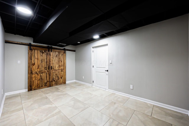 below grade area with a barn door, baseboards, and tile patterned floors