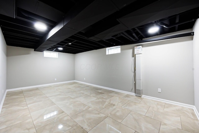 basement featuring light tile patterned flooring, plenty of natural light, and baseboards