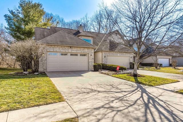 french provincial home featuring a front yard, a chimney, concrete driveway, a garage, and stone siding