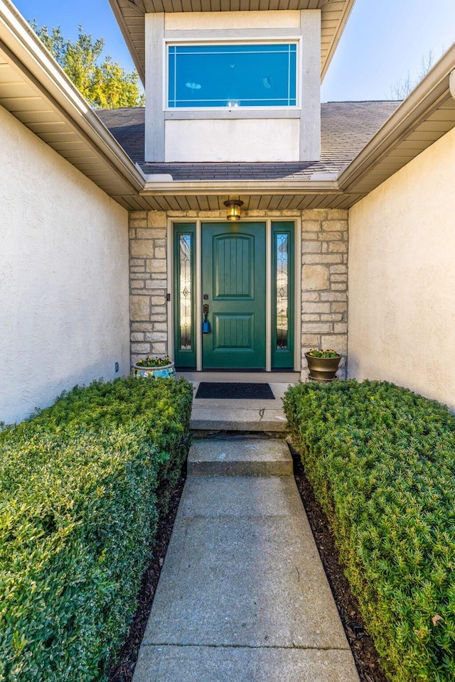 property entrance with stone siding, stucco siding, and a shingled roof