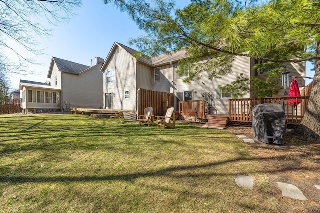 rear view of house with a wooden deck and a lawn