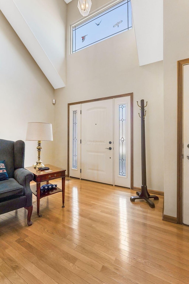 entrance foyer featuring a high ceiling, baseboards, light wood finished floors, and a chandelier