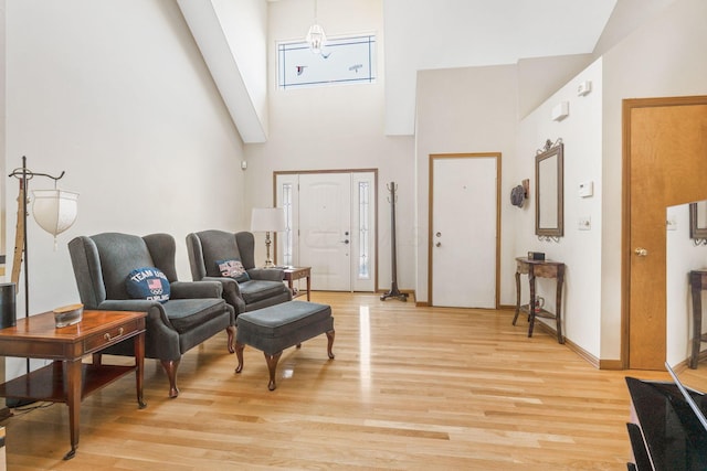 entrance foyer featuring baseboards, light wood-style floors, and a high ceiling