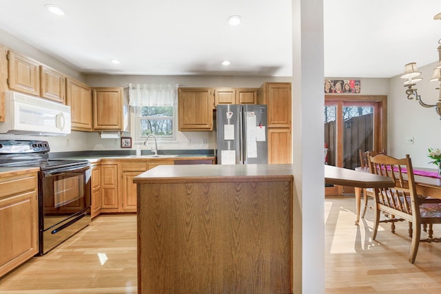 kitchen featuring white microwave, freestanding refrigerator, light wood-style floors, black electric range oven, and a sink