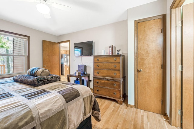 bedroom with freestanding refrigerator, light wood-type flooring, and ceiling fan