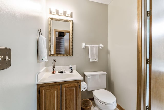 half bath with vanity, toilet, and baseboards