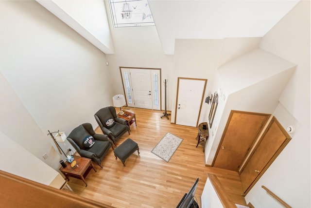 living area featuring light wood-type flooring and a towering ceiling