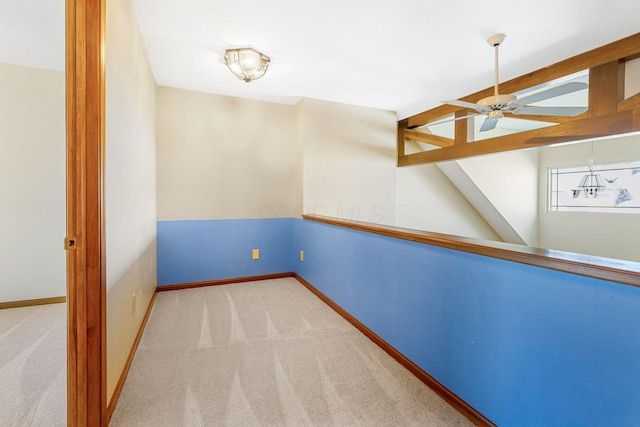 carpeted spare room with vaulted ceiling with beams, a ceiling fan, and baseboards