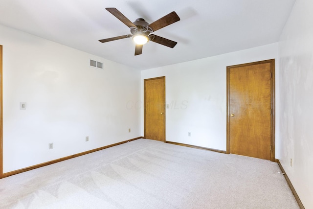 unfurnished bedroom featuring visible vents, baseboards, light colored carpet, and ceiling fan