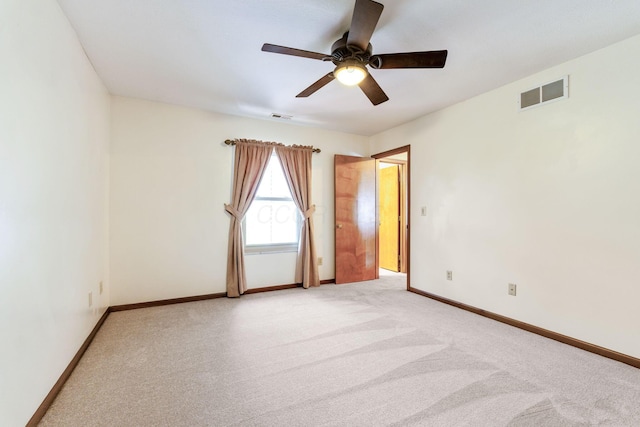 spare room featuring light carpet, visible vents, ceiling fan, and baseboards