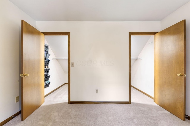 unfurnished bedroom featuring a spacious closet, carpet flooring, baseboards, and a closet