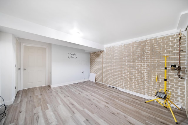 interior space featuring baseboards, light wood-type flooring, and brick wall