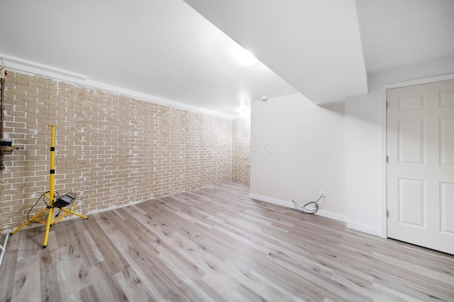 interior space featuring brick wall, baseboards, and wood finished floors