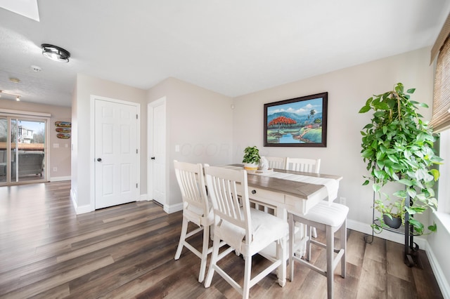 dining space with baseboards and dark wood finished floors