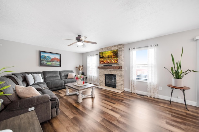 living room with a textured ceiling, wood finished floors, a fireplace, baseboards, and ceiling fan