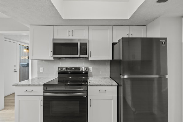 kitchen with stainless steel appliances, a textured ceiling, white cabinets, and decorative backsplash