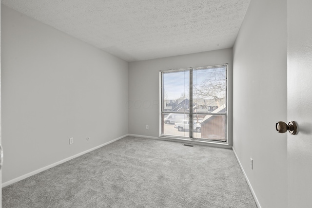 spare room with carpet, baseboards, and a textured ceiling