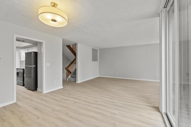 interior space featuring stairs, light wood-style floors, baseboards, and a textured ceiling