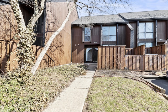 property entrance featuring fence and a shingled roof