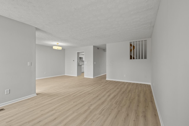 spare room featuring visible vents, baseboards, a textured ceiling, and light wood finished floors