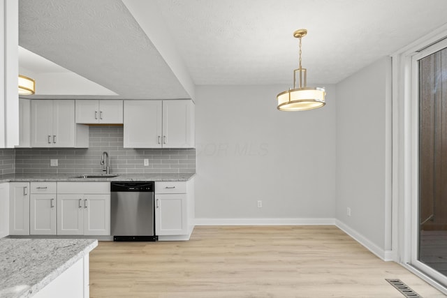 kitchen featuring visible vents, a sink, backsplash, light wood finished floors, and dishwasher