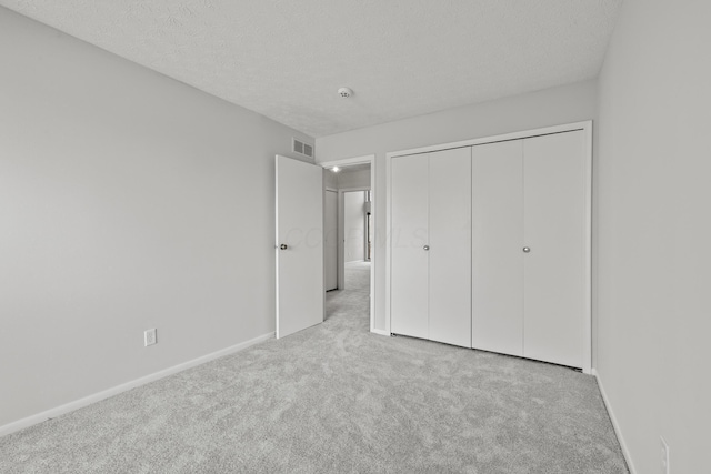 unfurnished bedroom with visible vents, carpet flooring, a textured ceiling, and baseboards