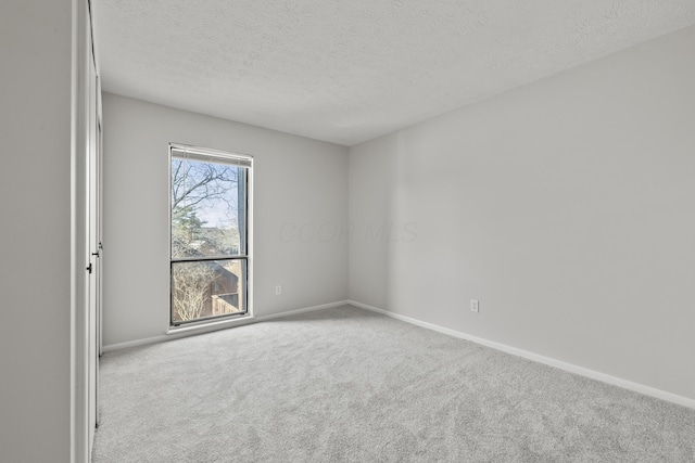 unfurnished room with carpet, baseboards, and a textured ceiling