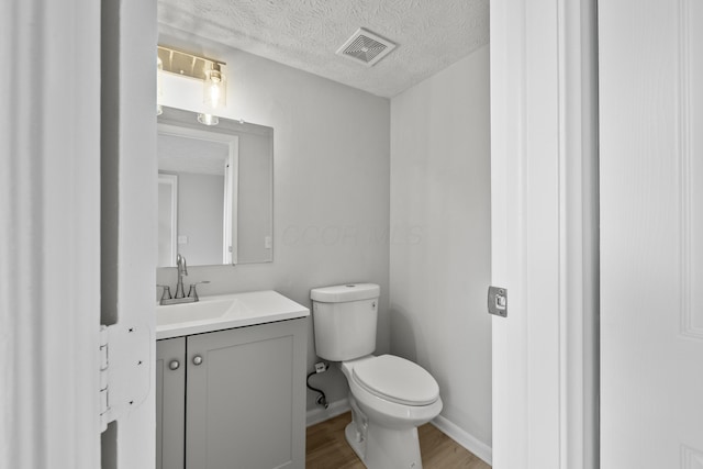 bathroom featuring vanity, wood finished floors, visible vents, a textured ceiling, and toilet