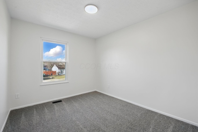 spare room with dark colored carpet, visible vents, baseboards, and a textured ceiling