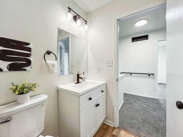 half bathroom with visible vents, baseboards, toilet, and vanity