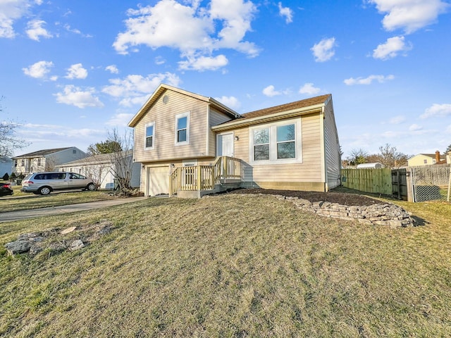 tri-level home with a garage, concrete driveway, a front lawn, and fence