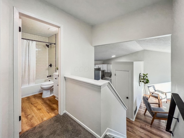 hall with an upstairs landing, baseboards, dark wood-type flooring, and lofted ceiling