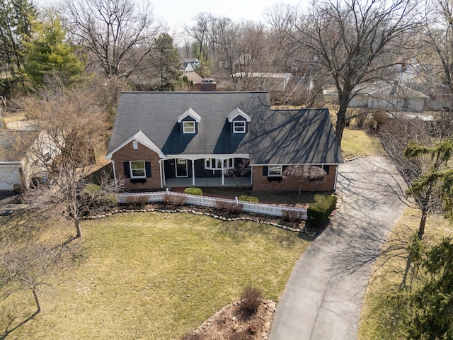 view of front facade with a front yard, covered porch, brick siding, and driveway