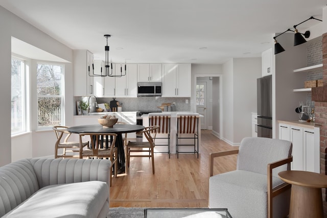 dining room featuring baseboards, a notable chandelier, and light wood finished floors