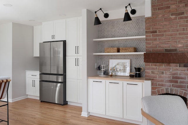 kitchen with open shelves, white cabinets, light wood-style floors, and freestanding refrigerator