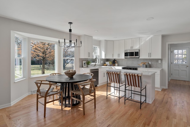 dining room featuring light wood-style flooring, a healthy amount of sunlight, and a chandelier