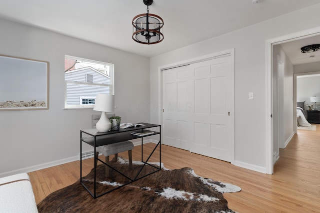 office space featuring an inviting chandelier, light wood-style flooring, and baseboards