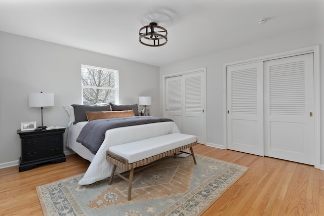 bedroom featuring wood finished floors, baseboards, and two closets