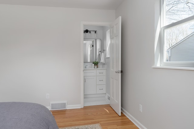 bedroom with visible vents, baseboards, ensuite bath, and light wood finished floors